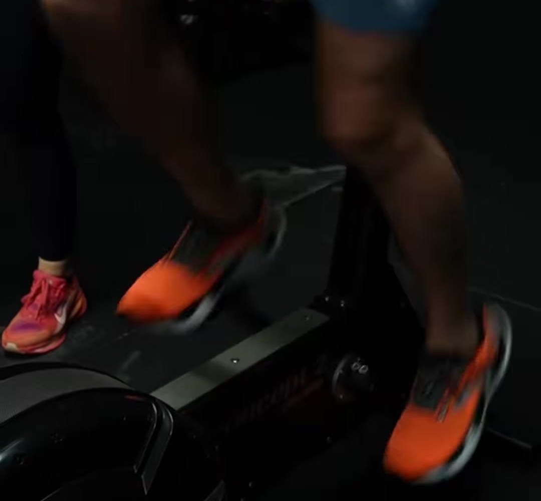 Orange trainers mid-stroke on a cardio machine