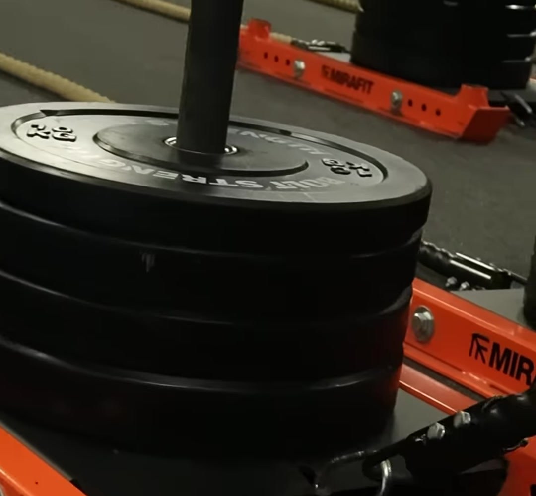 A loaded orange sled stacked with bumper plates